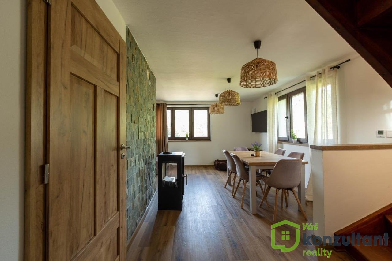 Jídelna s obývací částí a krbovými kamny v přízemí chaty